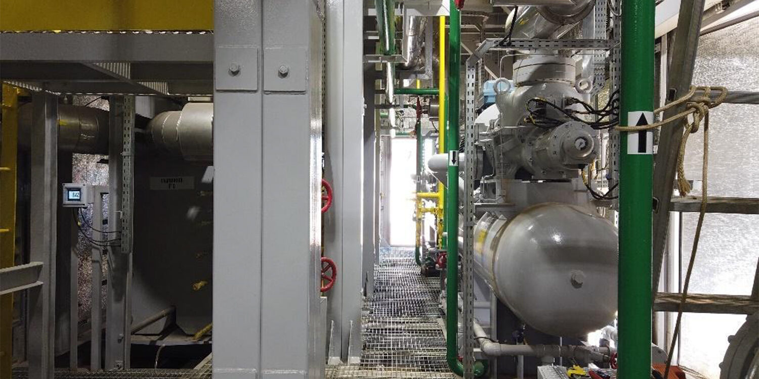 Interior de planta de refrigeração industrial com tubulações e equipamentos