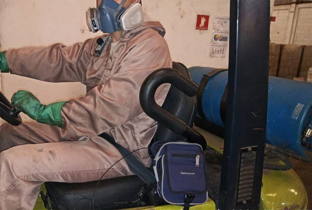Trabalhador com macacão e proteção respiratória durante operação industrial
