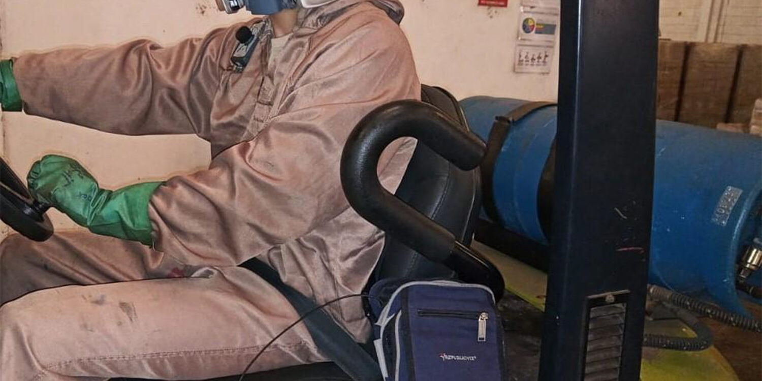Trabalhador com macacão e proteção respiratória durante operação industrial