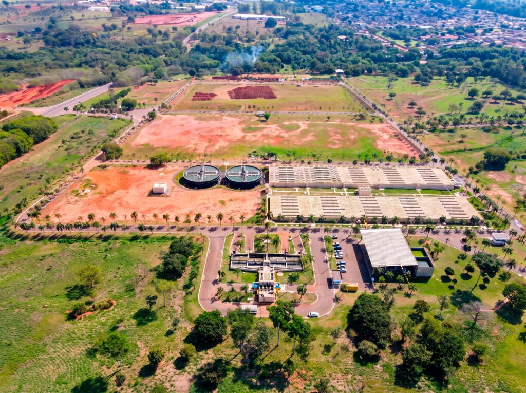 Vista aérea de estação de tratamento de esgoto com tanques circulares e leitos de secagem