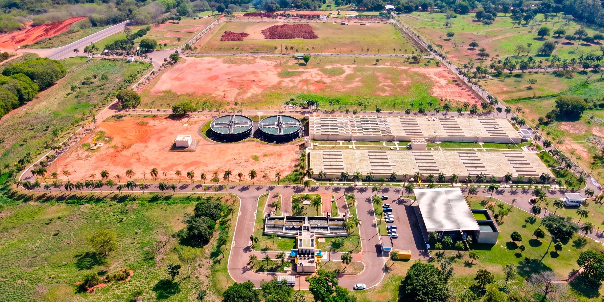 Vista aérea de estação de tratamento de esgoto com tanques circulares e leitos de secagem