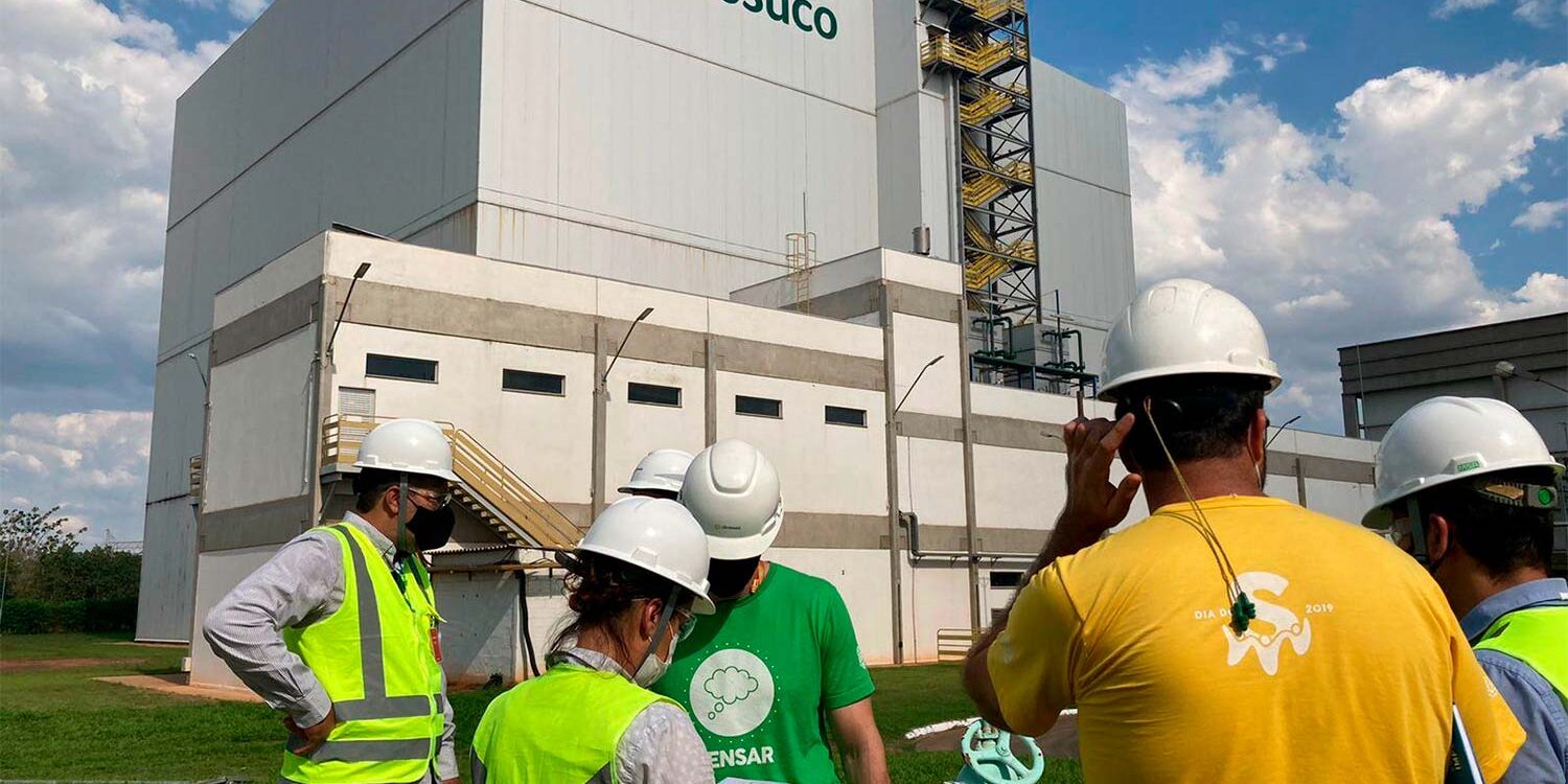 Equipe técnica reunida em frente à planta industrial da Citrosuco