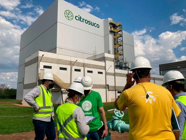 Equipe técnica reunida em frente à planta industrial da Citrosuco